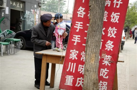 An elderly Chinese man talks to a child on a street of Daxing district in Beijing, China, in this photo taken Monday, April 25.